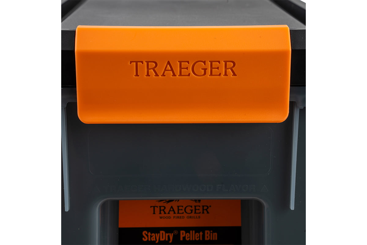 Close-up of the orange Traeger latch securing the pellet bin lid