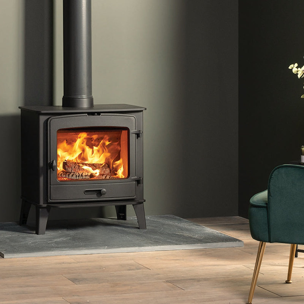 Stovax County 8 stove shown from the side beside a green armchair