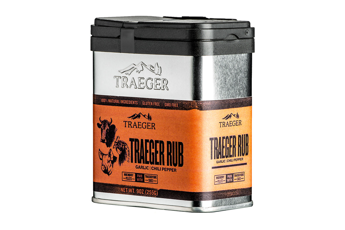 "Close-up view of a Traeger Rub container with a silver and black design. The label highlights its 100% natural ingredients, gluten-free, and GMO-free attributes. The rub flavor is described as garlic chili pepper. The bottom portion showcases a vibrant orange color with graphics of animals and pairing suggestions.