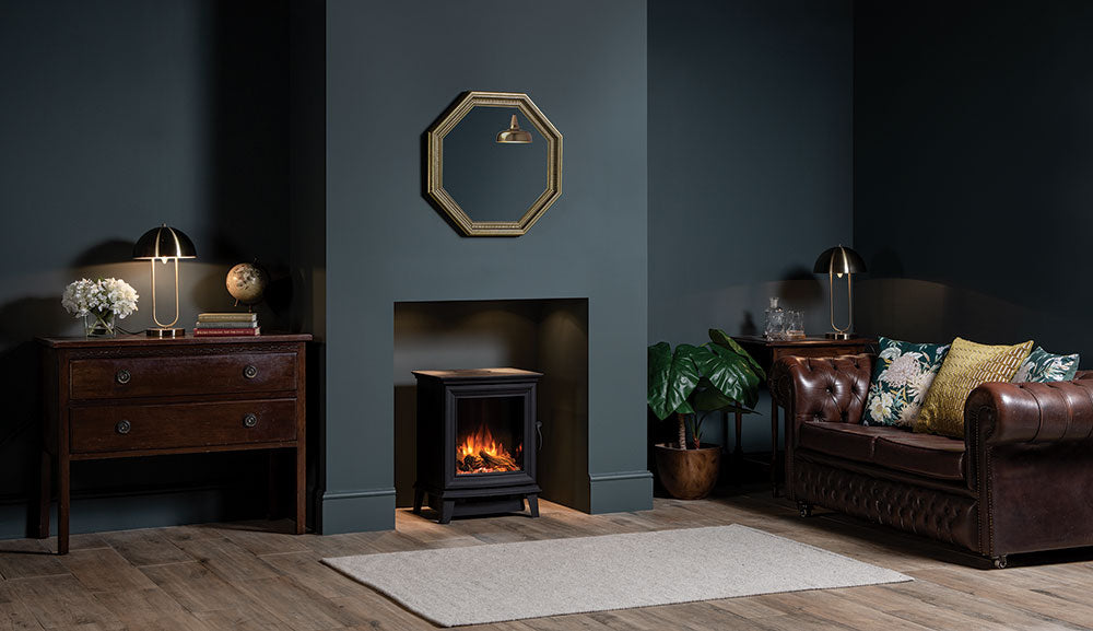 Gazco Chesterfield 5 electric stove in a dark teal living room beside a leather sofa