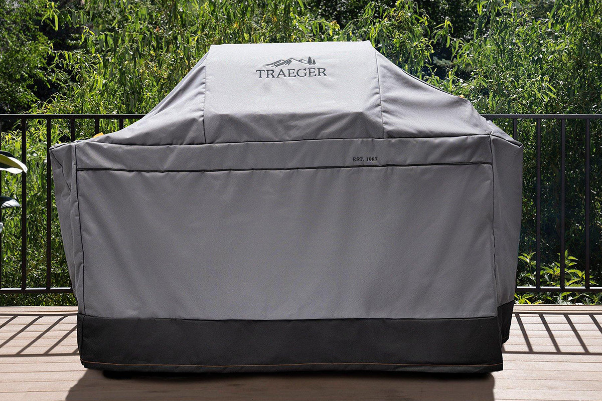 Traeger Ironwood grill under its grey full-length cover on an outdoor deck