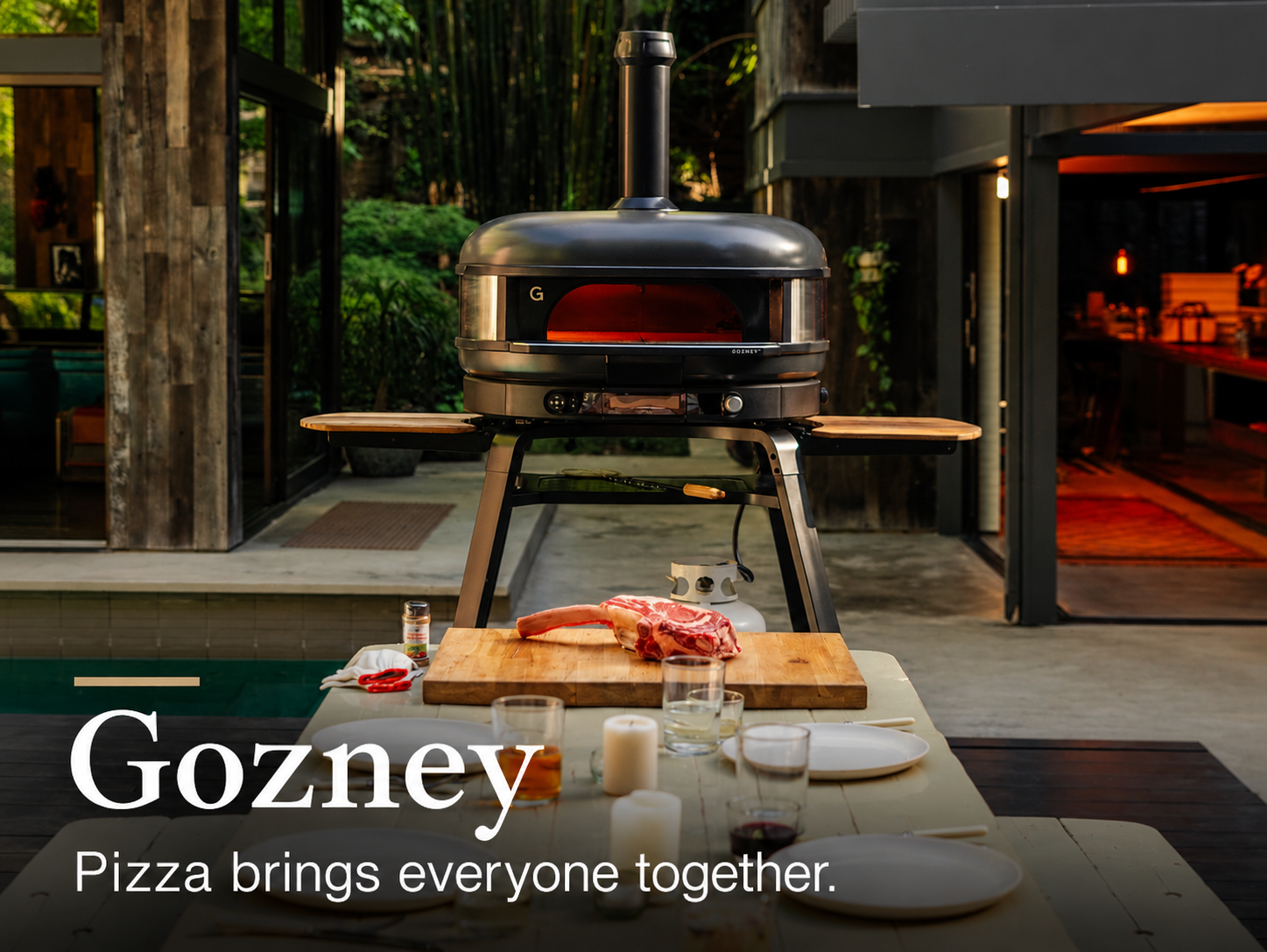 Gozney. Pizza brings everyone together. Gozney Dome XL oven beside an outdoor dining table