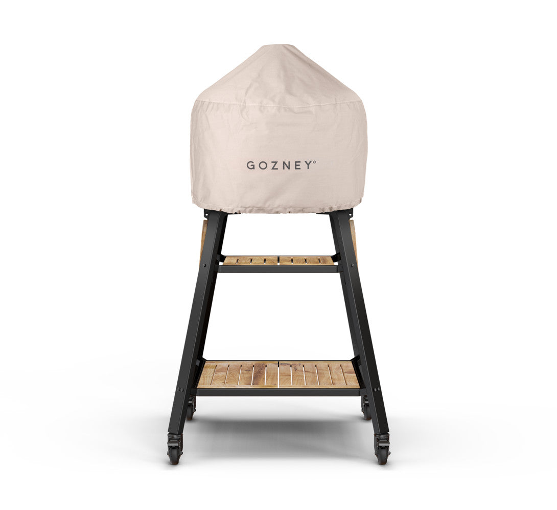 Cream Gozney Dome cover fitted over a pizza oven on a black wheeled stand with wooden shelves