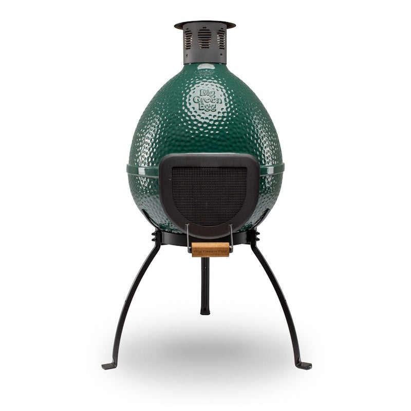 Green Big Green Egg chiminea on three black legs with a mesh front door and chimney cap