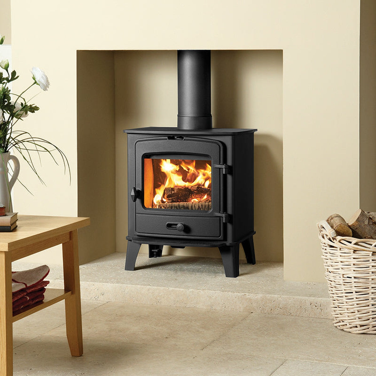 Stovax County 5 stove in a cream fireplace beside a basket of logs