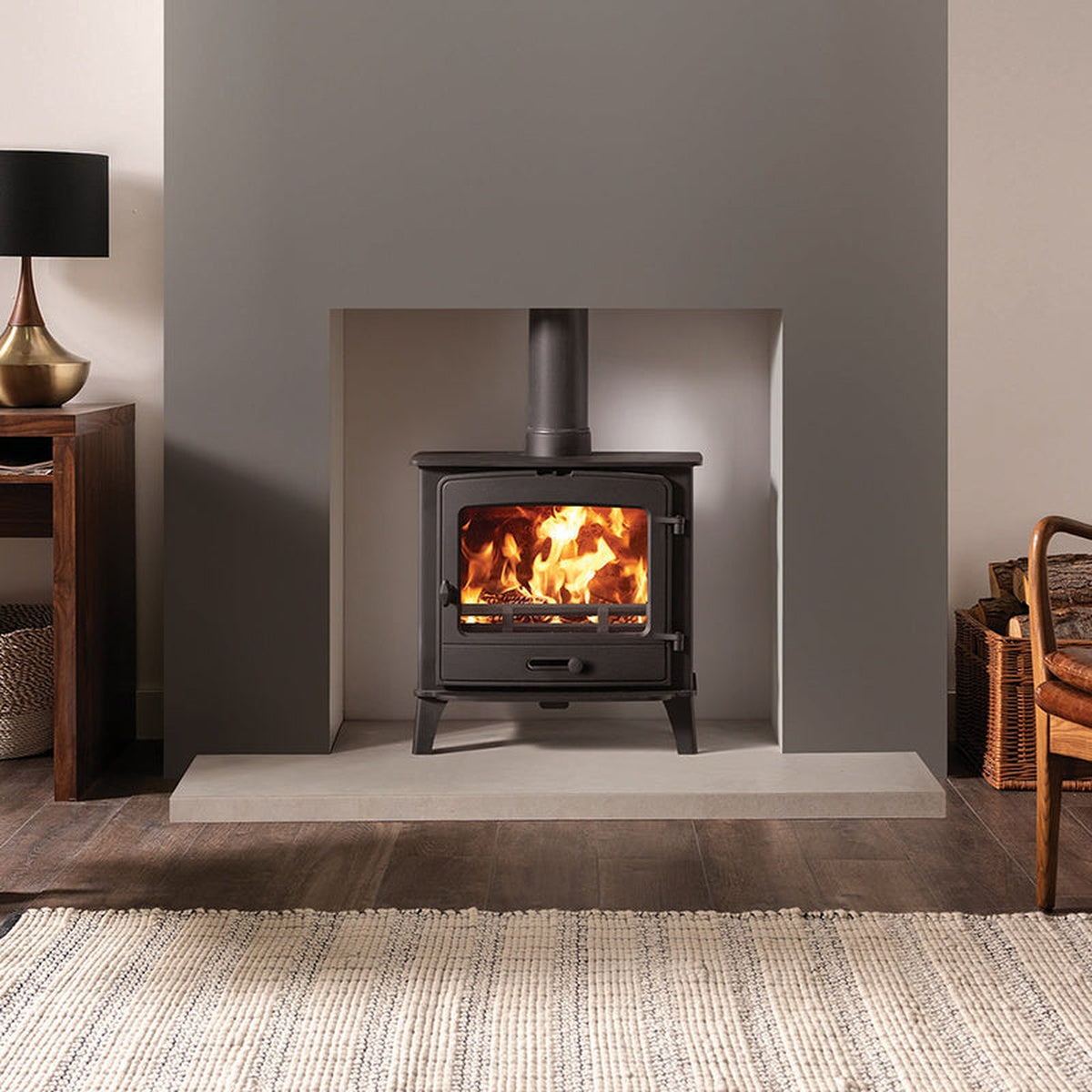 Stovax County 5 Wide stove in a white recess beside a log store