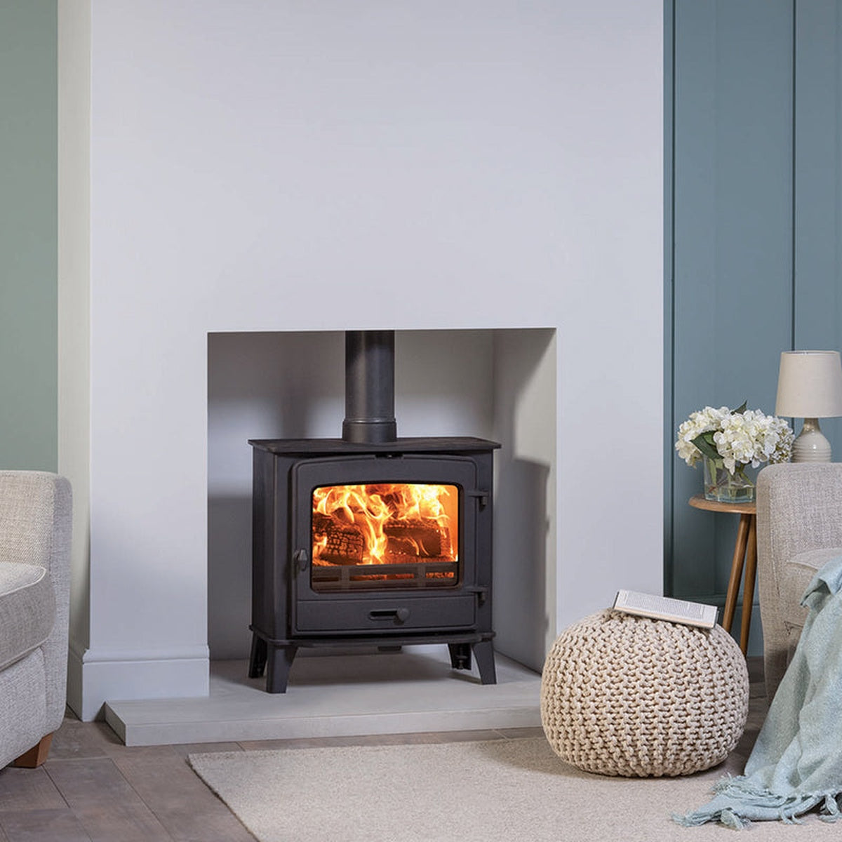 Stovax County 5 Wide stove in a white fireplace beside a sofa