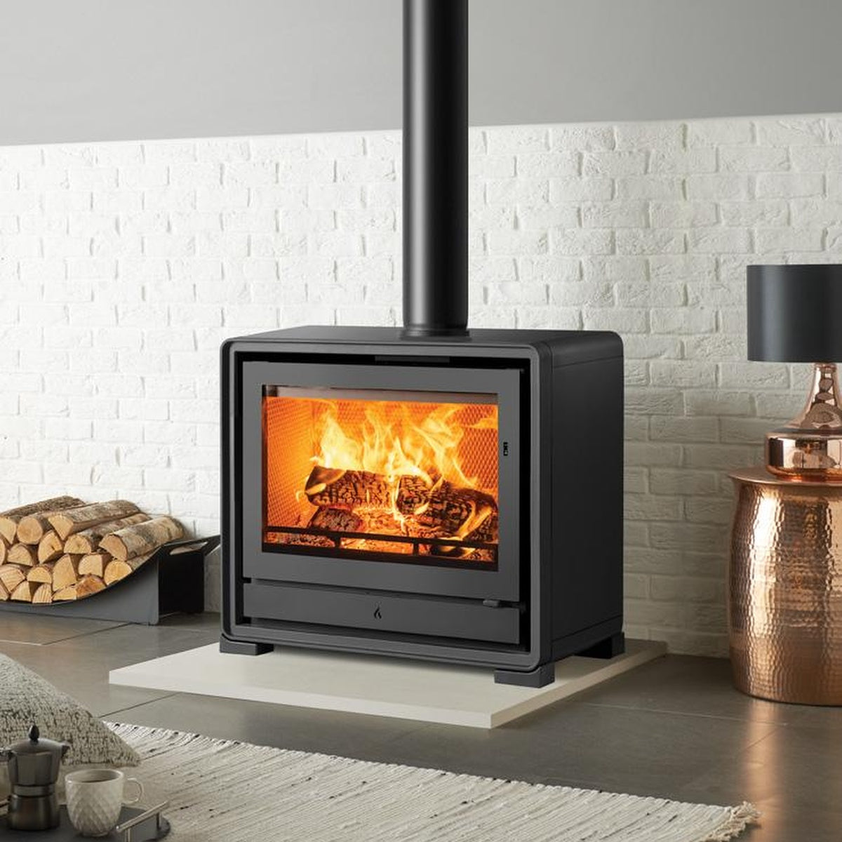 Stovax Riva2 66 freestanding fire with optional cast-iron feet in a white brick-lined opening