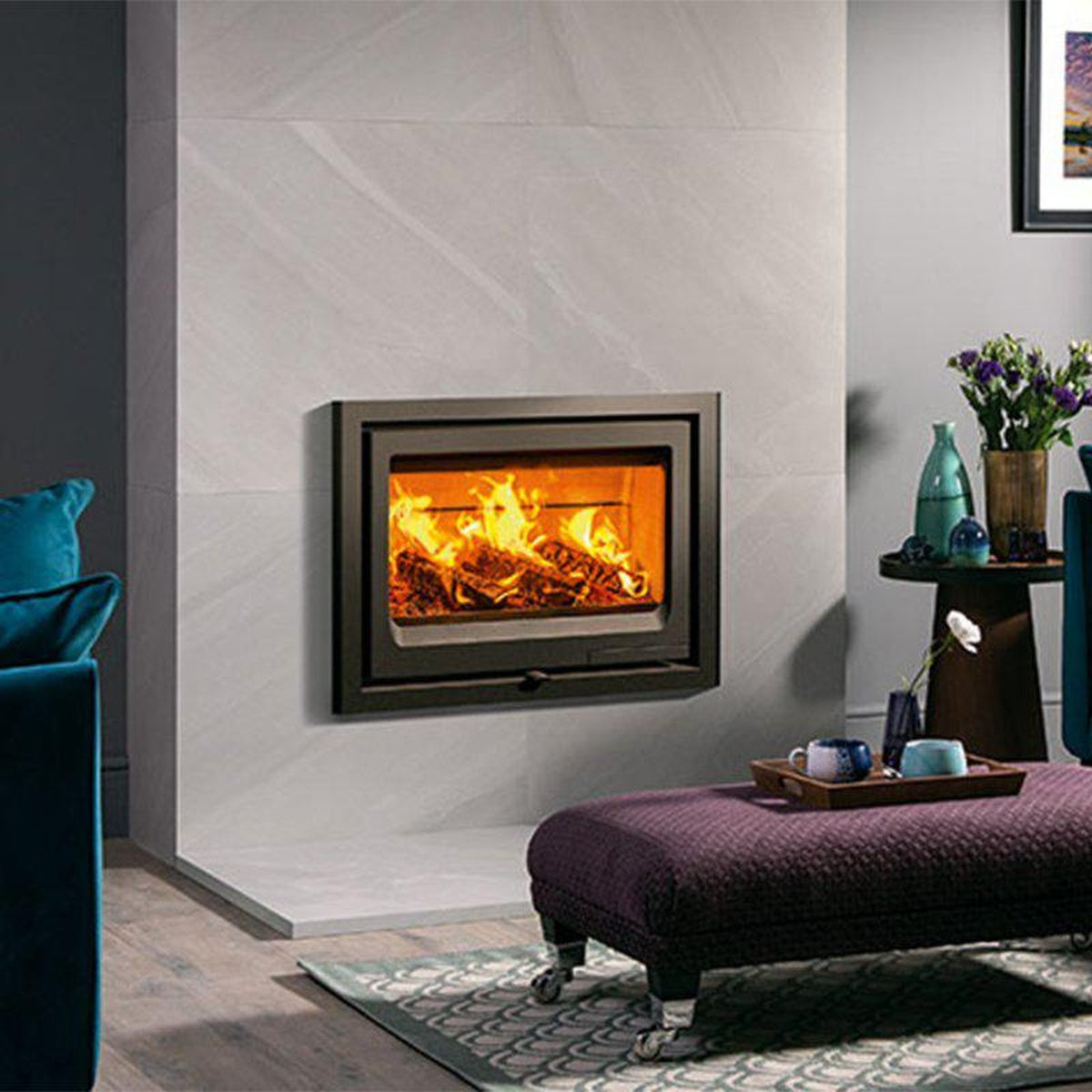 Stovax Vogue 700 Inset wood fire in a tiled wall beside a teal sofa