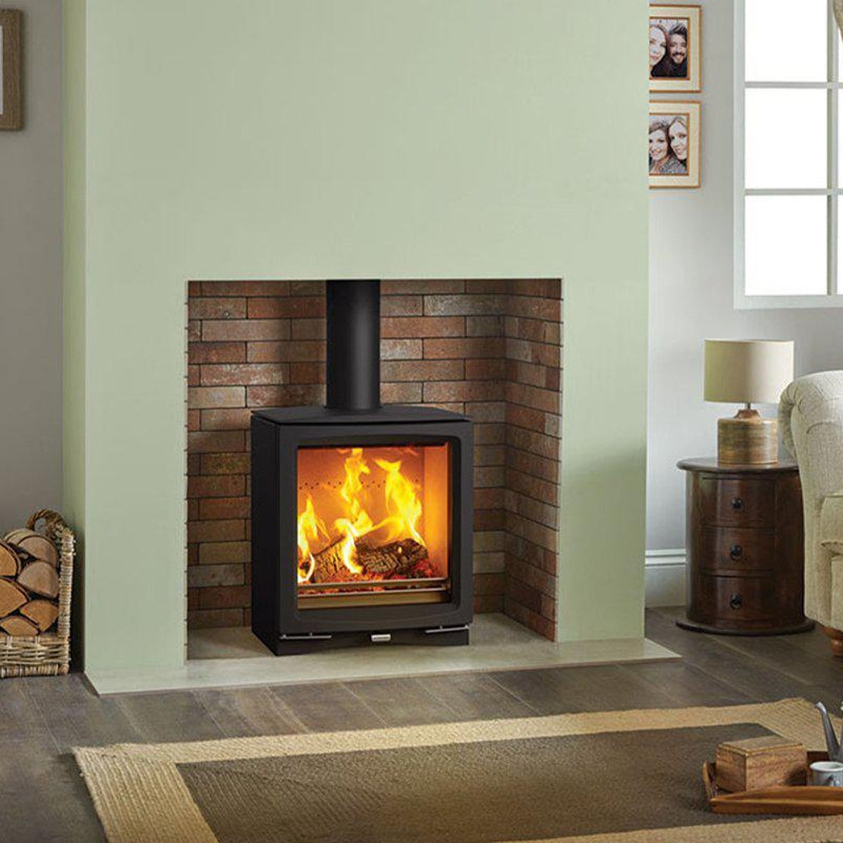 Stovax Vogue Medium stove in a brick fireplace against a green wall