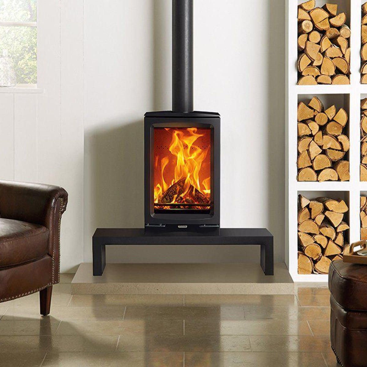 Stovax Vogue Midi T stove on a low bench beside stacked logs