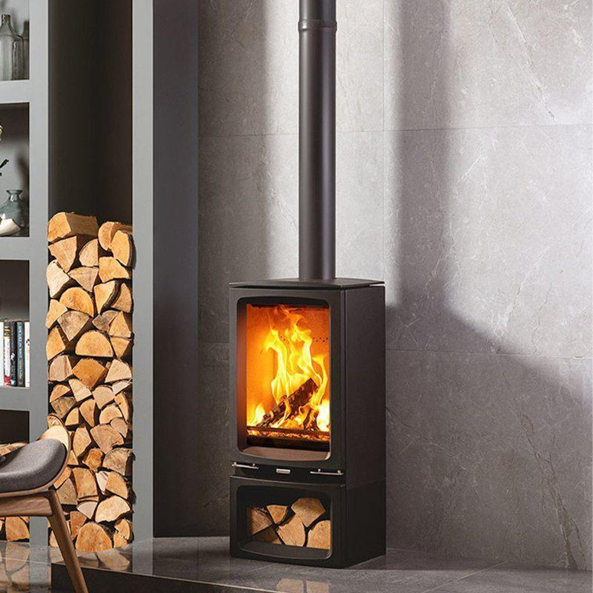 Stovax Vogue Midi T stove with Midline log-store base beside a grey armchair