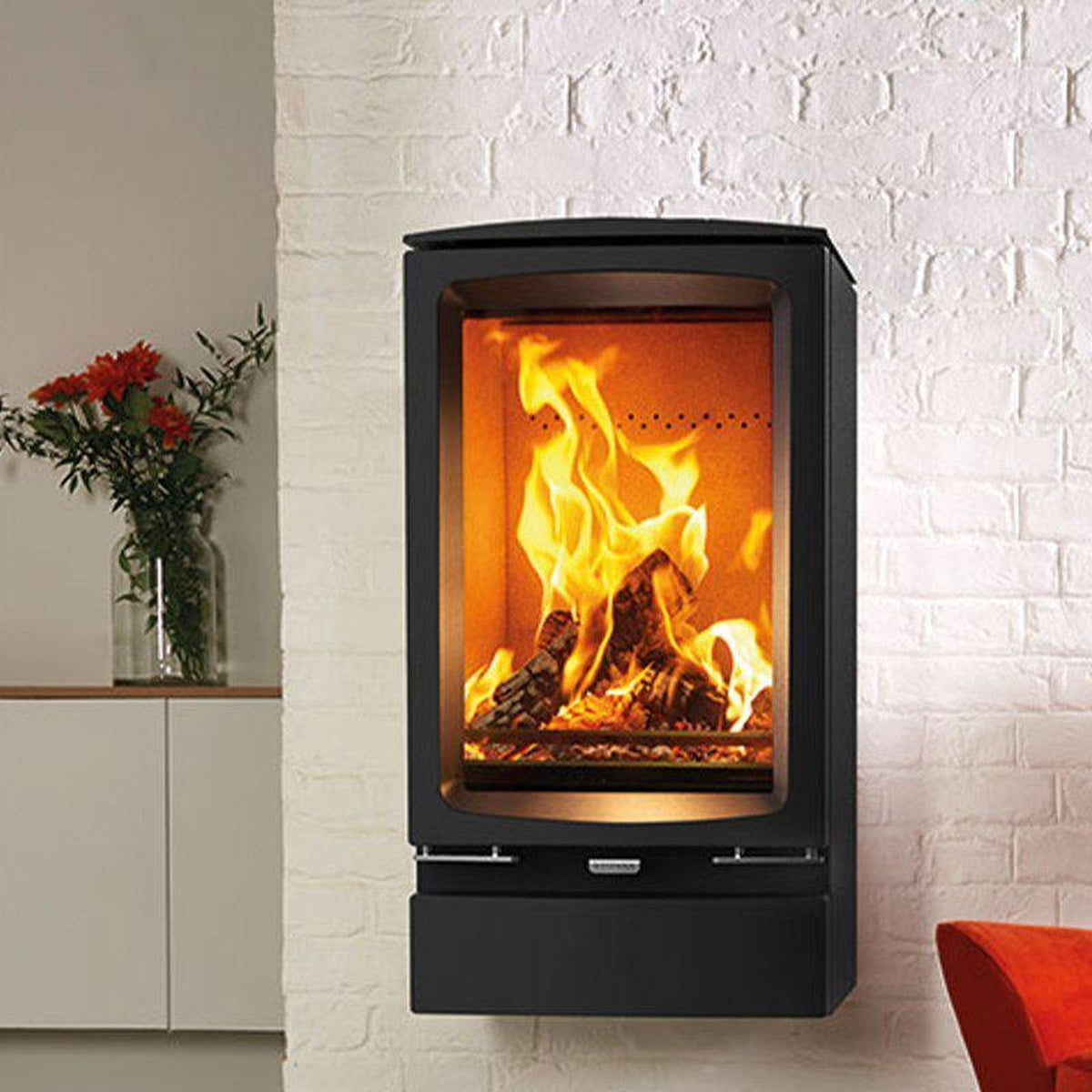 Stovax Vogue Midi T Wall Hung stove with plinth beside a red armchair