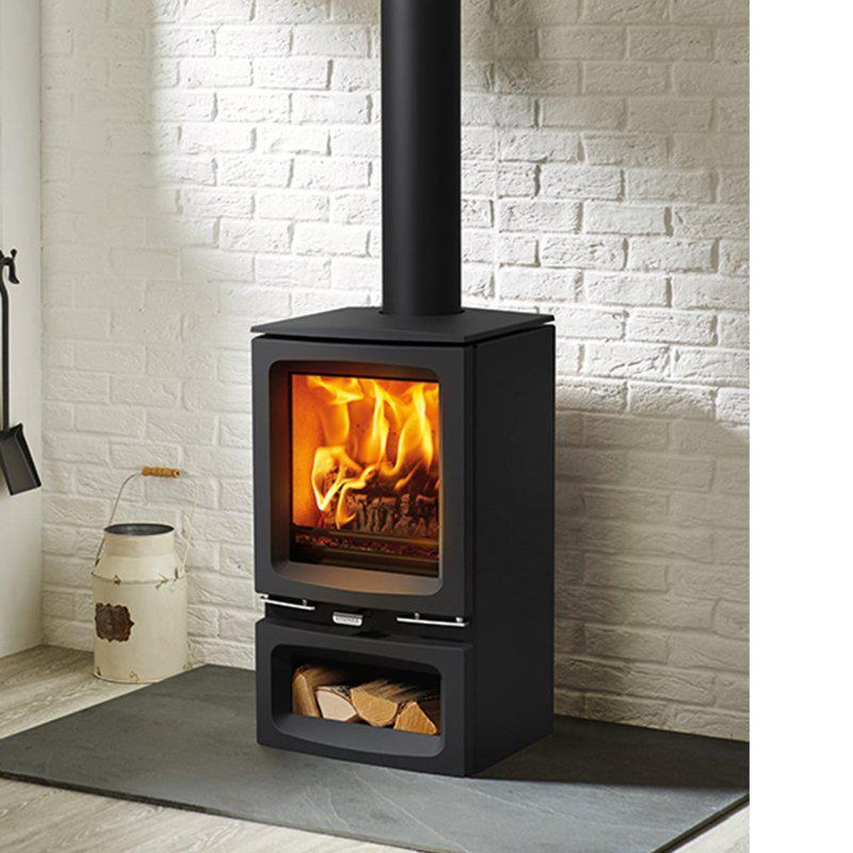 Stovax Vogue Small wood stove with Midline log-store base beside a white brick wall