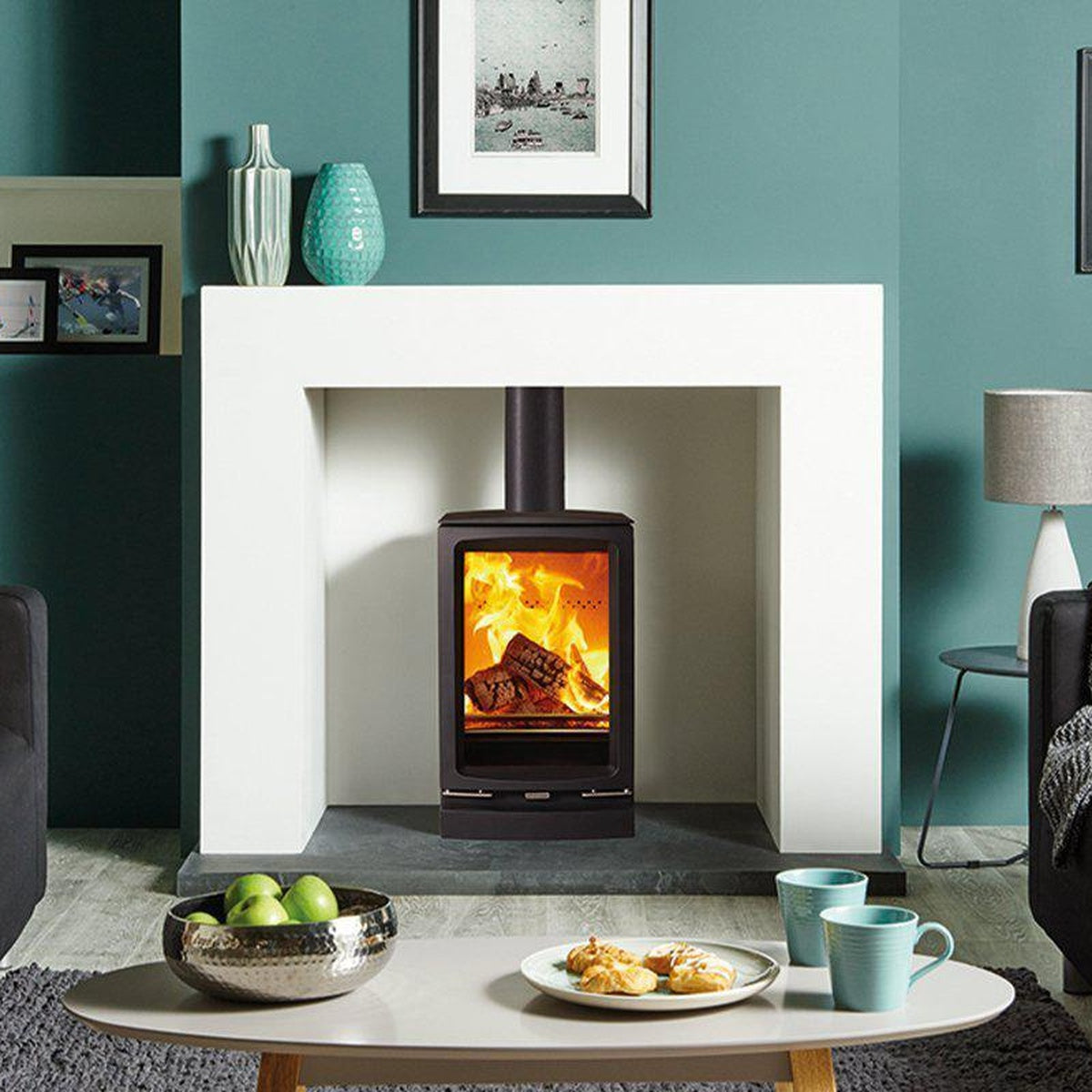 Stovax Vogue Small T stove with plinth in a fireplace against a teal wall
