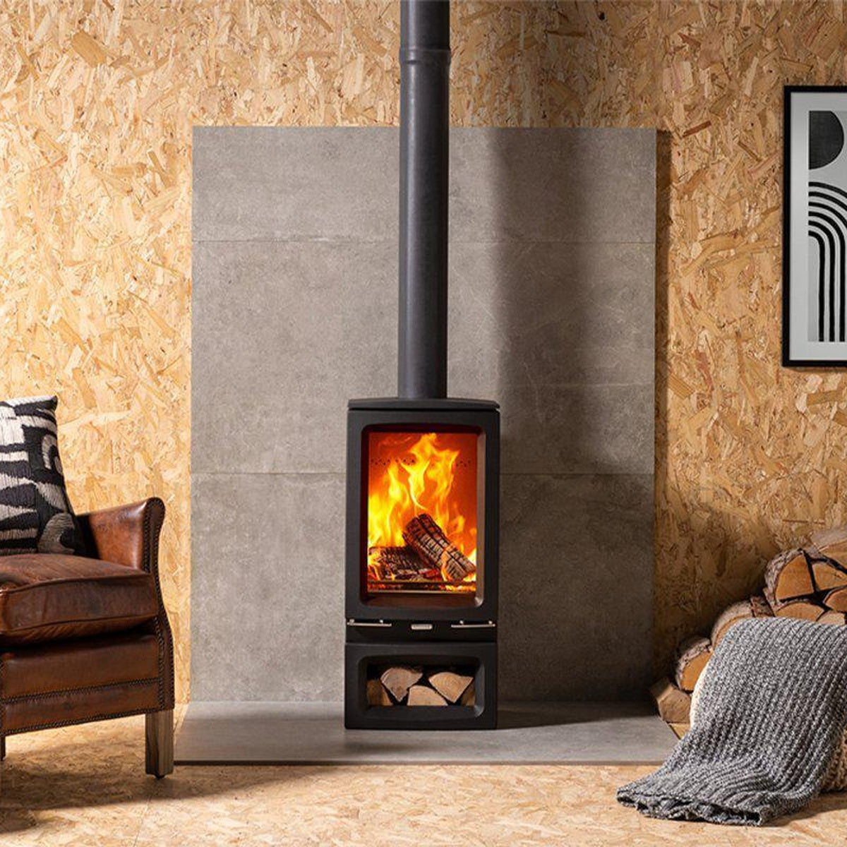 Stovax Vogue Small T stove with Midline log-store base beside a brown armchair