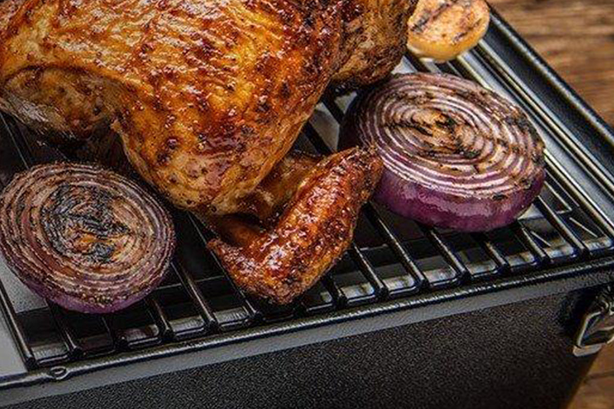 Grilled chicken and red onion halves on a Traeger grill