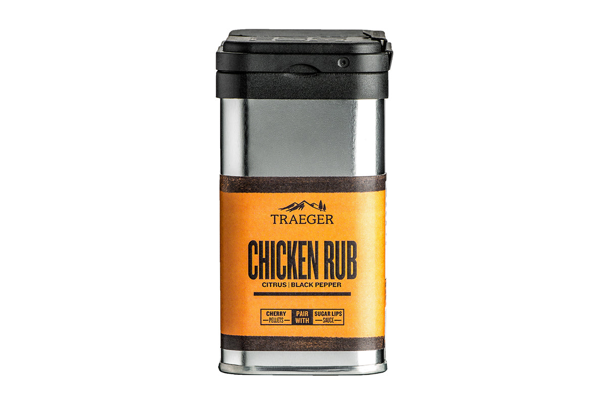 A box container labeled "TRAEGER CHICKEN RUB" with a silver body and orange accenting. The brand "TRAEGER" is featured above the product name. This rub is flavored with "Citrus | Black Pepper". The container has a black cap and displays recommendations like "CHERRY PELLETS" and "PAIR WITH SUGAR LIPS SAUCE" on the side. The overall design is sleek and modern.