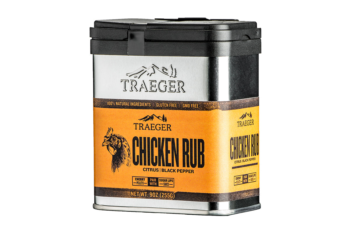A container of "TRAEGER CHICKEN RUB" with a silver body and vibrant orange labeling. The brand name "TRAEGER" is prominently displayed at the top with a silhouette of a chicken beneath it. The rub is described as "Citrus | Black Pepper". The label highlights that it contains "100% Natural Ingredients", is "Gluten Free", and "GMO Free". The container specifies a net weight of 9oz (255g).