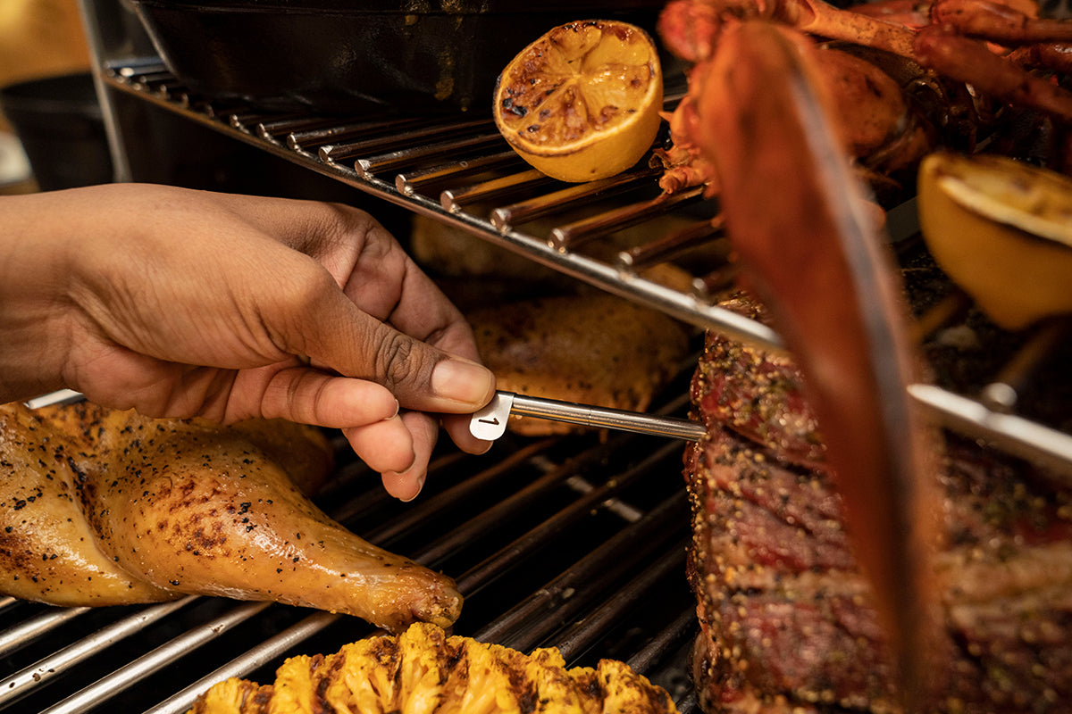 Person inserting a numbered Traeger x MEATER probe into a roast on the grill
