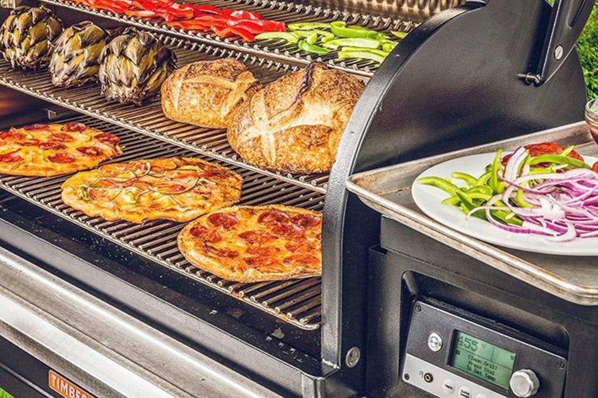 Traeger Timberline grill cooking pizzas, bread and vegetables on three levels