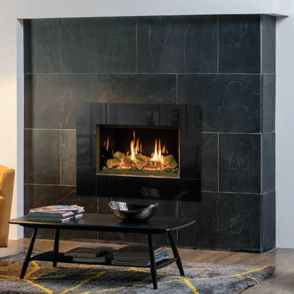 Gazco Riva2 600 Icon XS gas fire with black glass lining in a dark tiled fireplace wall