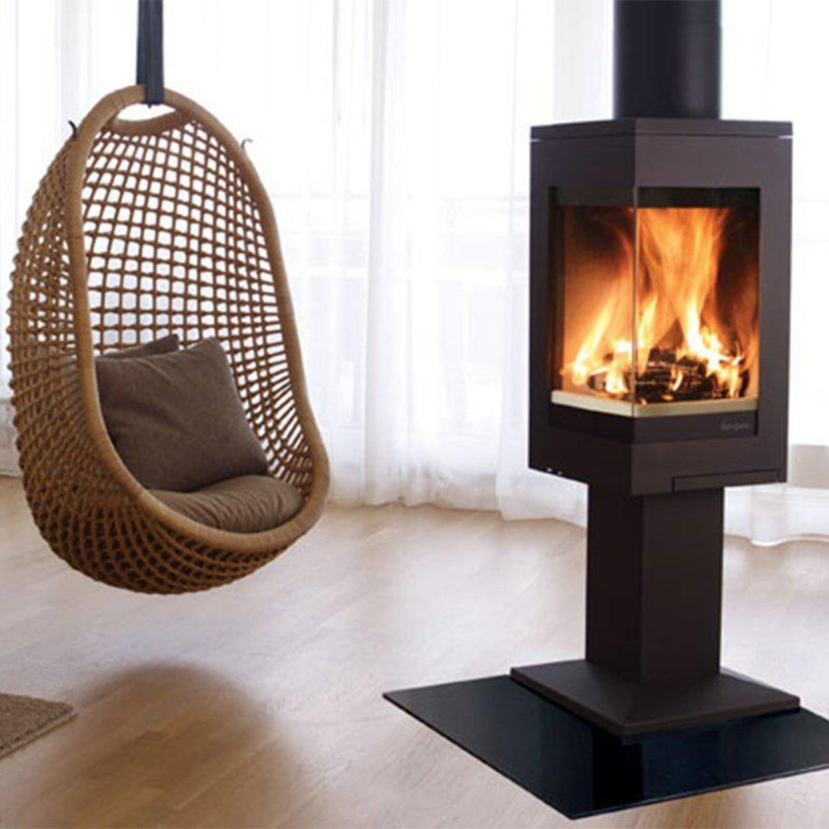 Nordpeis Quadro 1 pedestal wood stove beside a hanging chair