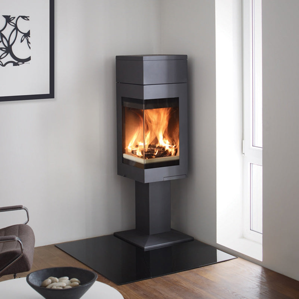 Nordpeis Quadro 1T wood stove with tall top and pedestal in a room setting