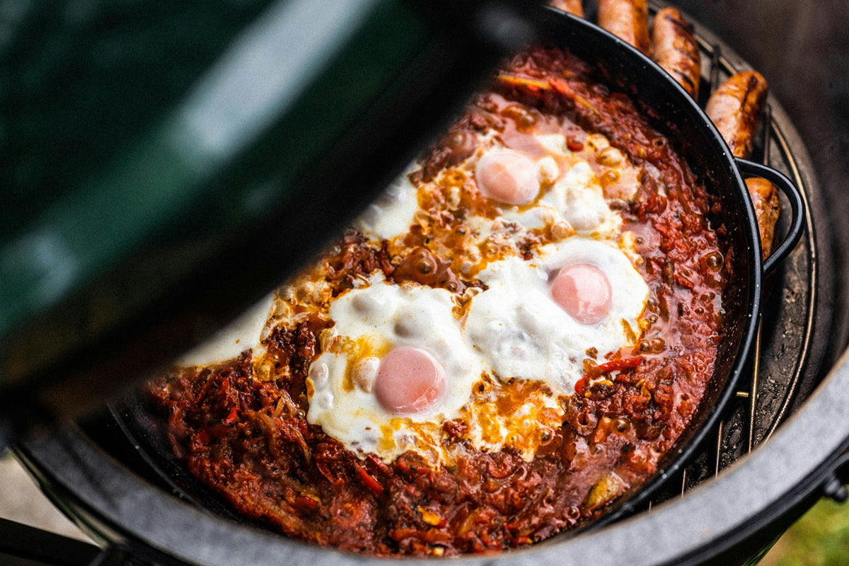 Cooking shakshuka with eggs on the Big Green Egg Paella Pan.