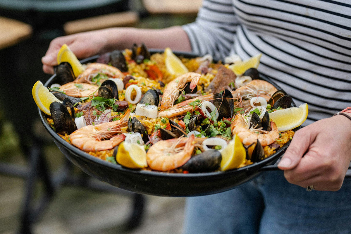 Paella with seafood and lemons served on the Big Green Egg Paella Pan.