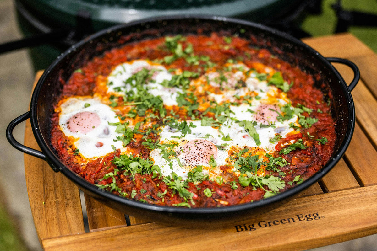 Shakshuka garnished with fresh herbs served on the Big Green Egg Paella Pan.