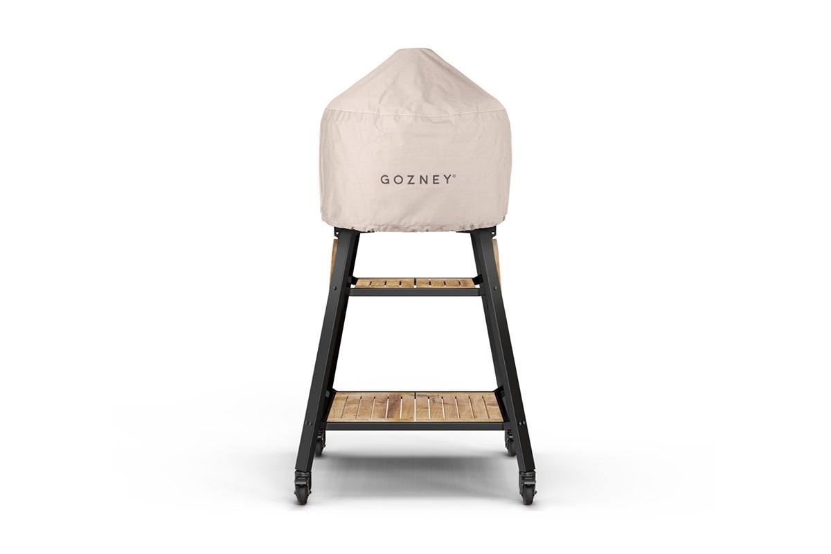 Cream Gozney Dome cover fitted over a pizza oven on a black wheeled stand with wooden shelves